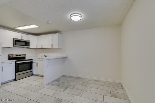 212 Orland St Unit 28, Las Vegas, NV 89107 - kitchen featuring stainless steel appliances, light countertops, white cabinetry, baseboards, and a textured ceiling