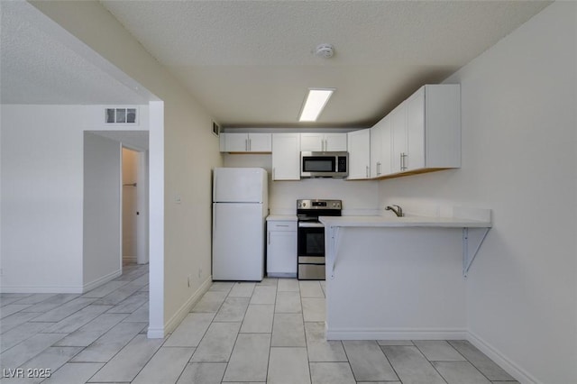 212 Orland St Unit 28, Las Vegas, NV 89107 - kitchen with appliances with stainless steel finishes, light countertops, white cabinets, a peninsula, and a textured ceiling