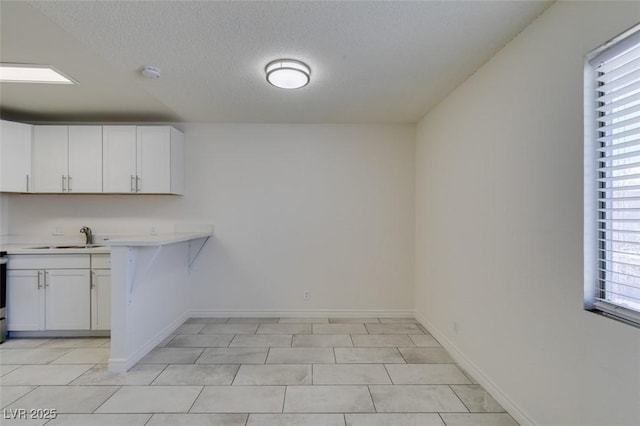 212 Orland St Unit 28, Las Vegas, NV 89107 - kitchen with light countertops, white cabinets, a textured ceiling, baseboards, and a sink