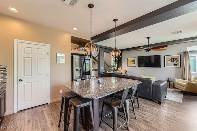 8121 Russell Creek Ct, Las Vegas, NV 89139 - kitchen featuring stainless steel fridge, a breakfast bar, light wood-style flooring, stone countertops, and a chandelier