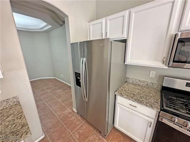 316 Lingering Ln, Henderson, NV 89012 - kitchen with appliances with stainless steel finishes, white cabinets, light stone counters, tile patterned flooring, and arched walkways