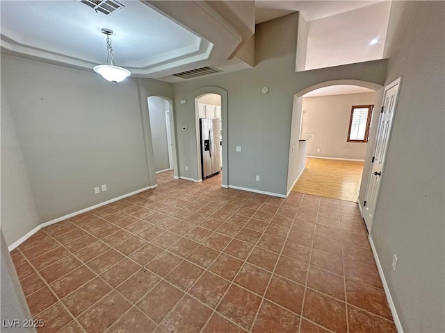 316 Lingering Ln, Henderson, NV 89012 - unfurnished room with arched walkways, a tray ceiling, baseboards, and dark tile patterned floors