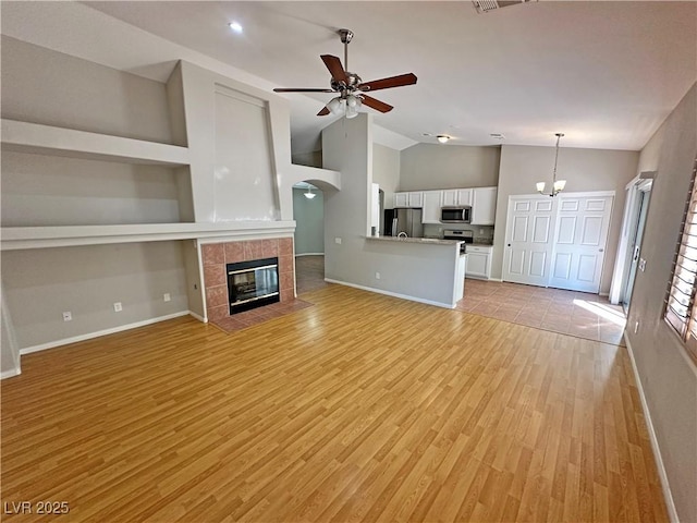 316 Lingering Ln, Henderson, NV 89012 - unfurnished living room with lofted ceiling, ceiling fan, light wood finished floors, baseboards, and a tile fireplace