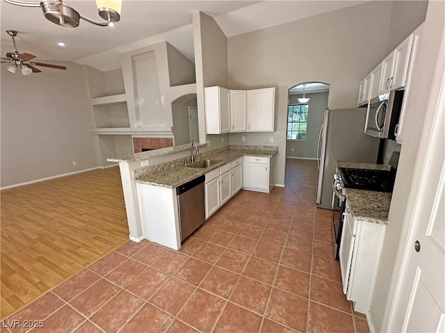 316 Lingering Ln, Henderson, NV 89012 - kitchen with stainless steel appliances, arched walkways, a sink, ceiling fan, and vaulted ceiling