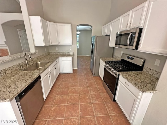 316 Lingering Ln, Henderson, NV 89012 - kitchen featuring appliances with stainless steel finishes, arched walkways, a sink, white cabinets, and light stone counters
