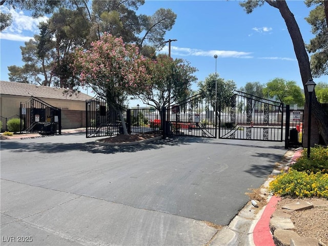 1667 Marion Bennet Dr, Las Vegas, NV 89106 - view of asphalt road featuring a gate, curbs, street lighting, and a gated entry