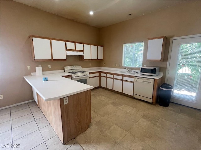 1667 Marion Bennet Dr, Las Vegas, NV 89106 - kitchen with white appliances, under cabinet range hood, light countertops, a peninsula, and plenty of natural light