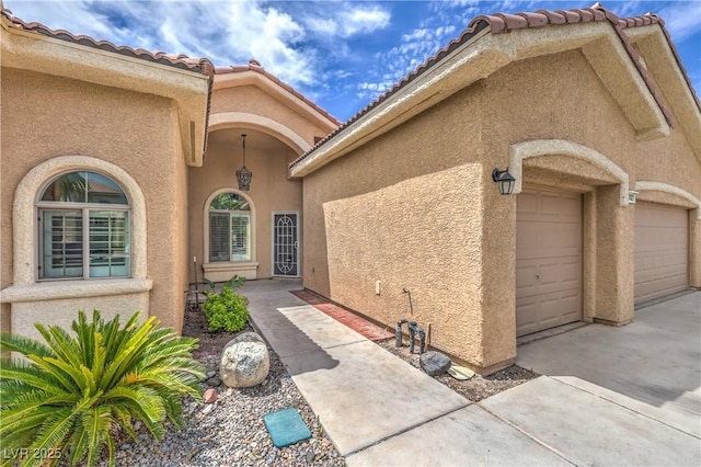 7427 Page Ranch Ct, Las Vegas, NV 89131 - entrance to property featuring a garage, stucco siding, a tiled roof, and driveway