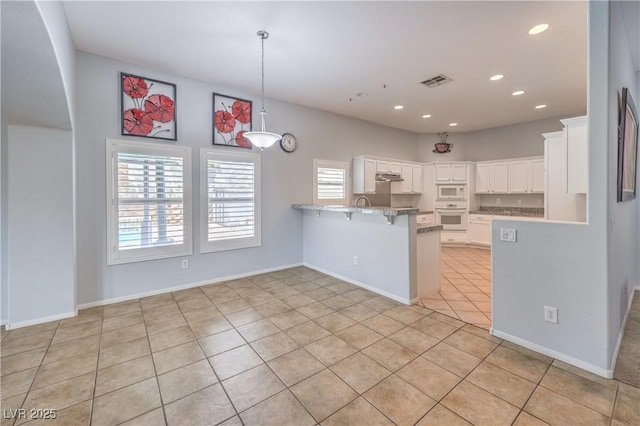 7427 Page Ranch Ct, Las Vegas, NV 89131 - kitchen featuring white appliances, a peninsula, light tile patterned flooring, white cabinetry, and a kitchen breakfast bar
