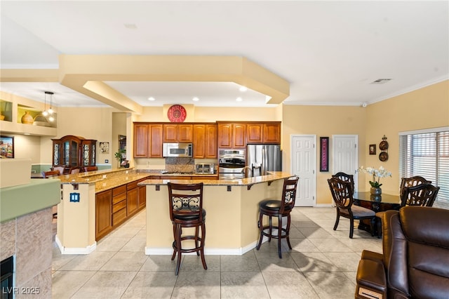 5940 Vizzi Ct, Las Vegas, NV 89131 - kitchen featuring stainless steel appliances, a breakfast bar area, light tile patterned flooring, brown cabinets, and light stone countertops