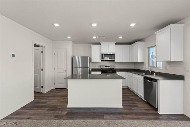 6197 Blood Lily Ave, Las Vegas, NV 89122 - kitchen with stainless steel appliances, a sink, dark countertops, white cabinets, and baseboards