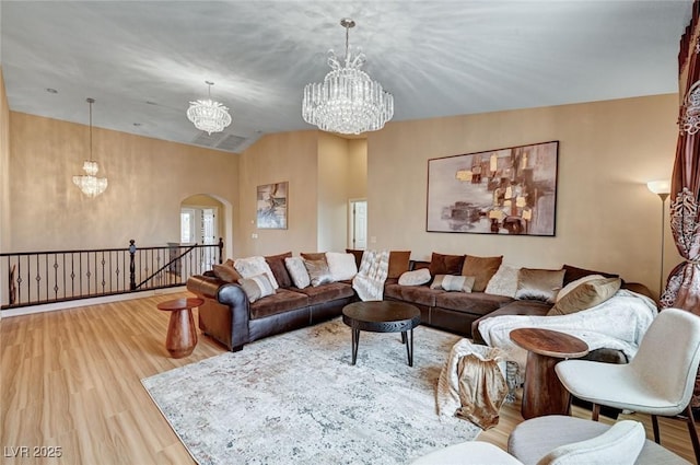 8223 Saddleback Ledge Ave, Las Vegas, NV 89147 - living room with a chandelier, arched walkways, wood finished floors, and vaulted ceiling