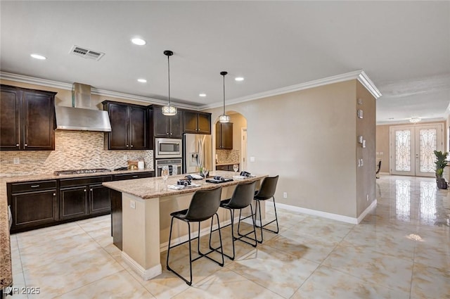 8223 Saddleback Ledge Ave, Las Vegas, NV 89147 - kitchen with stainless steel appliances, wall chimney exhaust hood, arched walkways, ornamental molding, and tasteful backsplash