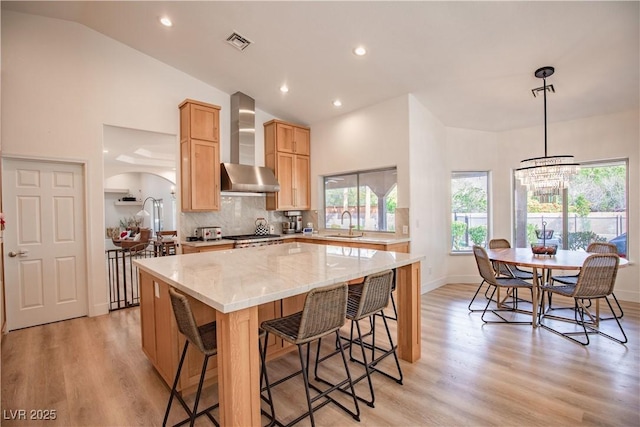 3236 Cliff Sieler Ct, Las Vegas, NV 89117 - kitchen with wall chimney exhaust hood, a center island, light wood finished floors, healthy amount of natural light, and high vaulted ceiling