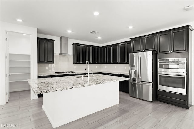 767 Tallgrass St, Las Vegas, NV 89138 - kitchen with stainless steel appliances, wall chimney range hood, a sink, dark cabinets, and backsplash