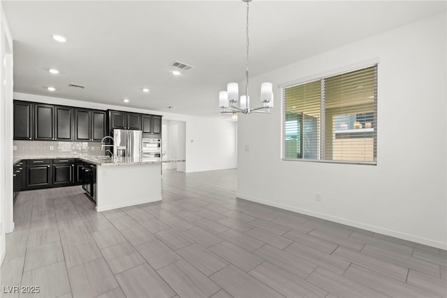 767 Tallgrass St, Las Vegas, NV 89138 - kitchen with stainless steel fridge with ice dispenser, a chandelier, open floor plan, tasteful backsplash, and recessed lighting