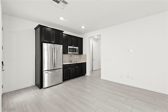 767 Tallgrass St, Las Vegas, NV 89138 - kitchen with appliances with stainless steel finishes, dark cabinetry, tasteful backsplash, a sink, and baseboards