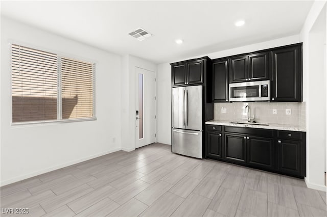 767 Tallgrass St, Las Vegas, NV 89138 - kitchen with stainless steel appliances, a sink, dark cabinets, decorative backsplash, and baseboards