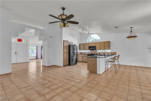 6405 Break Point Ave, Las Vegas, NV 89130 - kitchen with refrigerator with ice dispenser, black microwave, a kitchen bar, track lighting, and a peninsula