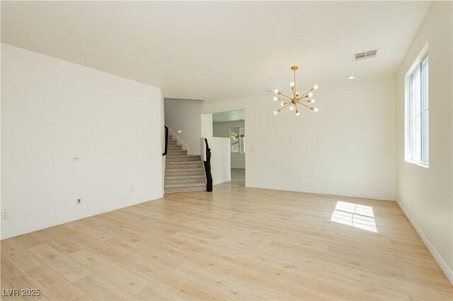 8224 Cassis Ct, Las Vegas, NV 89117 - unfurnished room with a chandelier, stairway, light wood-style floors, and baseboards