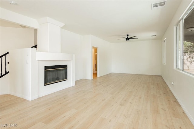 8224 Cassis Ct, Las Vegas, NV 89117 - unfurnished living room with a ceiling fan, light wood-style floors, and a glass covered fireplace