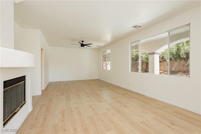 8224 Cassis Ct, Las Vegas, NV 89117 - unfurnished living room with light wood-type flooring, a glass covered fireplace, and ceiling fan