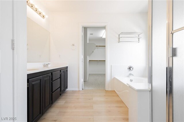 8224 Cassis Ct, Las Vegas, NV 89117 - bathroom featuring double vanity, wood finished floors, a garden tub, and a walk in closet