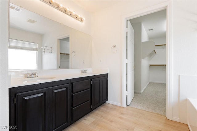 8224 Cassis Ct, Las Vegas, NV 89117 - bathroom featuring double vanity, wood finished floors, a spacious closet, and baseboards