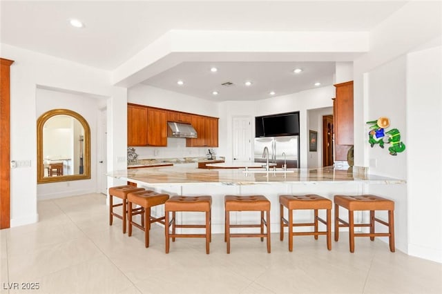 20 Kittansett Loop, Henderson, NV 89052 - kitchen featuring under cabinet range hood, stainless steel fridge, a sink, a peninsula, and a breakfast bar