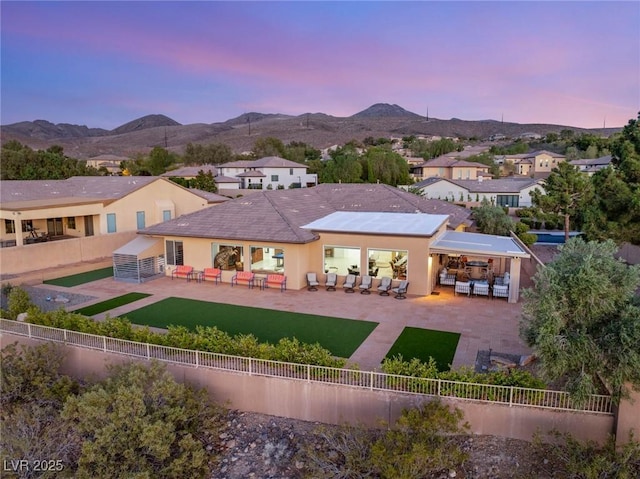 20 Kittansett Loop, Henderson, NV 89052 - back of property at dusk with an outdoor living space, a fenced backyard, a patio, a mountain view, and stucco siding