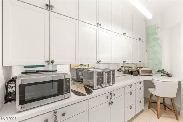 20 Kittansett Loop, Henderson, NV 89052 - kitchen featuring stainless steel microwave, light countertops, and white cabinetry