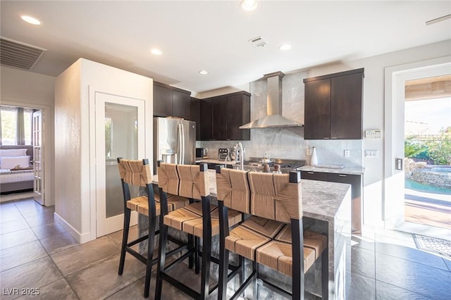 340 Autumn Palace Ct, Las Vegas, NV 89144 - kitchen featuring wall chimney range hood, stainless steel fridge with ice dispenser, decorative backsplash, dark brown cabinetry, and recessed lighting