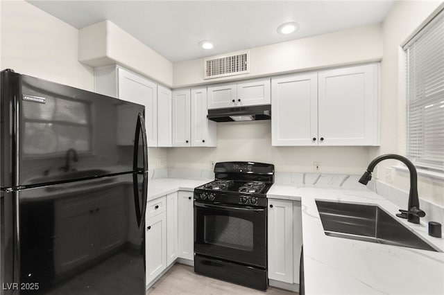 7566 Glowing Ember Ct Unit 101, Las Vegas, NV 89130 - kitchen with black appliances, under cabinet range hood, a sink, light stone countertops, and light wood finished floors