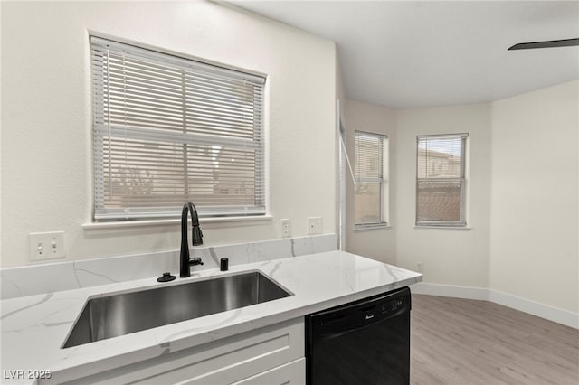 7566 Glowing Ember Ct Unit 101, Las Vegas, NV 89130 - kitchen featuring dishwasher, a sink, light wood-type flooring, light stone countertops, and baseboards