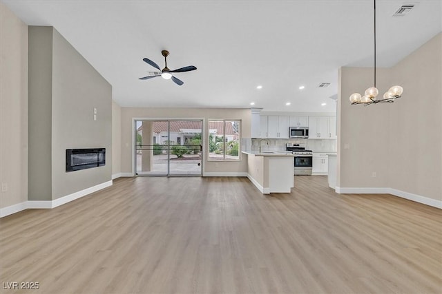 8513 Festival Dr, Las Vegas, NV 89134 - unfurnished living room featuring ceiling fan, light wood-style floors, baseboards, a glass covered fireplace, and a sink