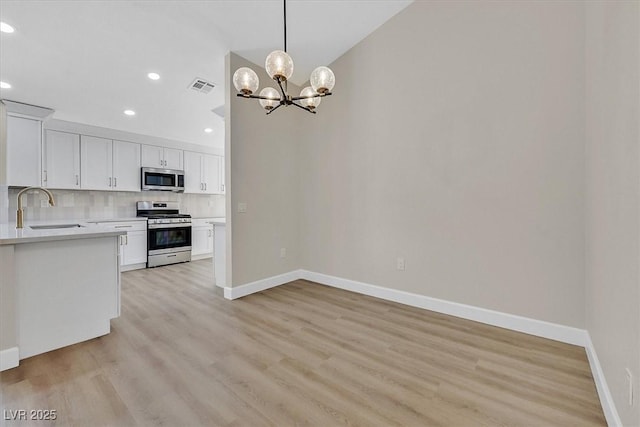 8513 Festival Dr, Las Vegas, NV 89134 - kitchen with stainless steel appliances, a sink, light countertops, baseboards, and a chandelier