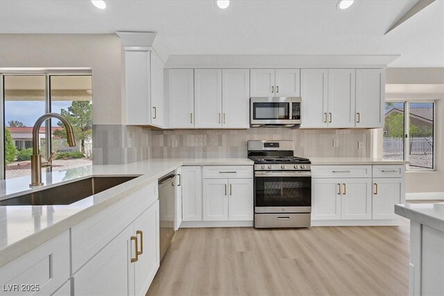 8513 Festival Dr, Las Vegas, NV 89134 - kitchen with stainless steel appliances, a sink, recessed lighting, white cabinets, and light wood finished floors