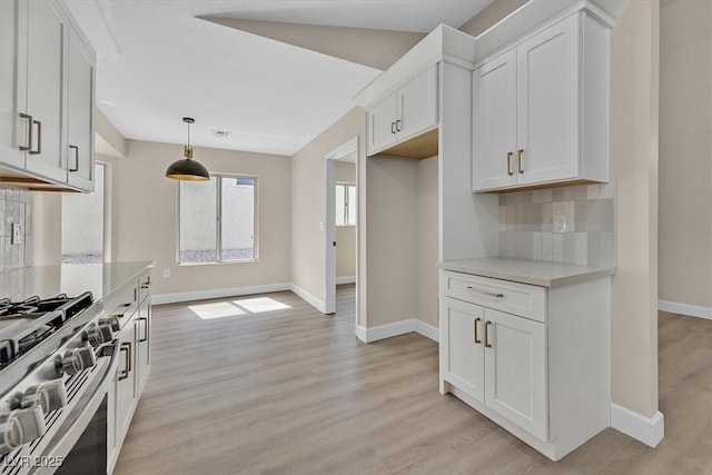 8513 Festival Dr, Las Vegas, NV 89134 - kitchen with stainless steel gas stove, light countertops, baseboards, tasteful backsplash, and light wood finished floors