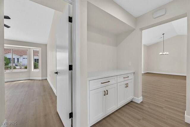 8513 Festival Dr, Las Vegas, NV 89134 - corridor with light wood finished floors, baseboards, lofted ceiling, and a chandelier