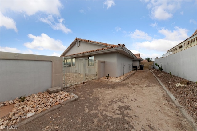 1060 Calico Ridge Dr, Henderson, NV 89011 - view of side of home with a tiled roof, a gate, and stucco siding