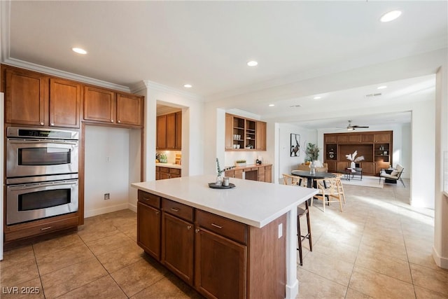 7466 Matilda St, Las Vegas, NV 89113 - kitchen with double oven, light tile patterned flooring, brown cabinets, a kitchen island, and light countertops