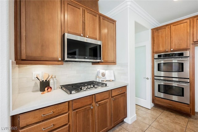 7466 Matilda St, Las Vegas, NV 89113 - kitchen with appliances with stainless steel finishes, decorative backsplash, light countertops, light tile patterned floors, and brown cabinetry