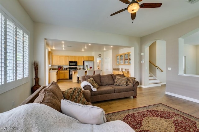 2418 Brockton Way, Henderson, NV 89074 - living area featuring a ceiling fan, light wood finished floors, arched walkways, and stairway