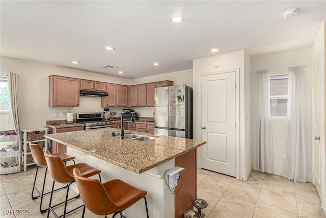 9690 Langden Brook St, Las Vegas, NV 89178 - kitchen featuring appliances with stainless steel finishes, a sink, a kitchen bar, light tile patterned floors, and under cabinet range hood