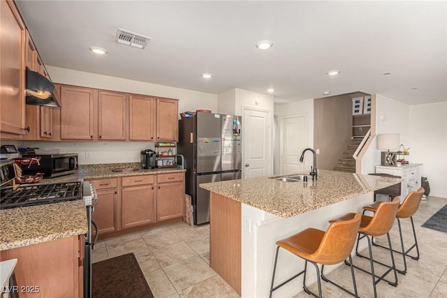 9690 Langden Brook St, Las Vegas, NV 89178 - kitchen featuring a sink, stainless steel appliances, exhaust hood, light stone counters, and a kitchen island with sink