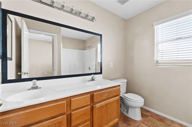5307 Wild Orchid St, North Las Vegas, NV 89031 - bathroom featuring toilet, double vanity, a shower, tile patterned floors, and baseboards