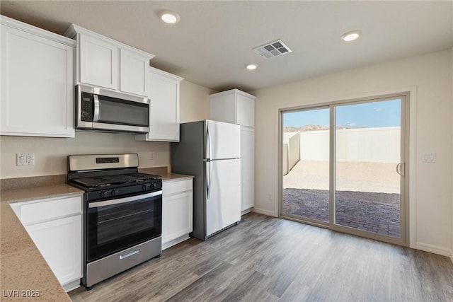 1716 Desert Path Ave, North Las Vegas, NV 89032 - kitchen with stainless steel appliances, white cabinetry, light wood-style flooring, baseboards, and recessed lighting