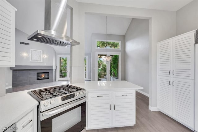 5008 Shoal Creek Cir, Las Vegas, NV 89113 - kitchen featuring stainless steel range with gas cooktop, wall chimney range hood, light countertops, white cabinetry, and a peninsula