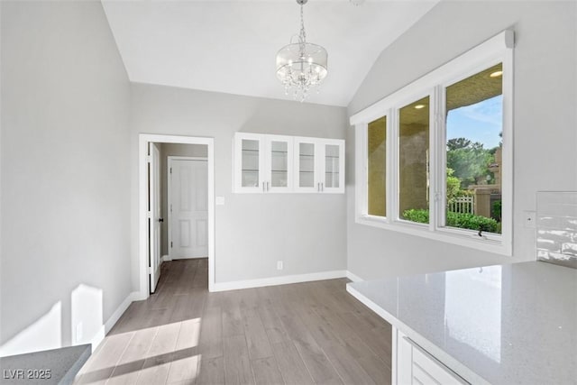5008 Shoal Creek Cir, Las Vegas, NV 89113 - unfurnished dining area with a chandelier, lofted ceiling, light wood finished floors, and baseboards
