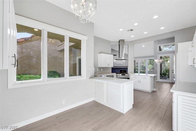 5008 Shoal Creek Cir, Las Vegas, NV 89113 - kitchen with wall chimney exhaust hood, stainless steel range oven, a peninsula, light countertops, and light wood-type flooring